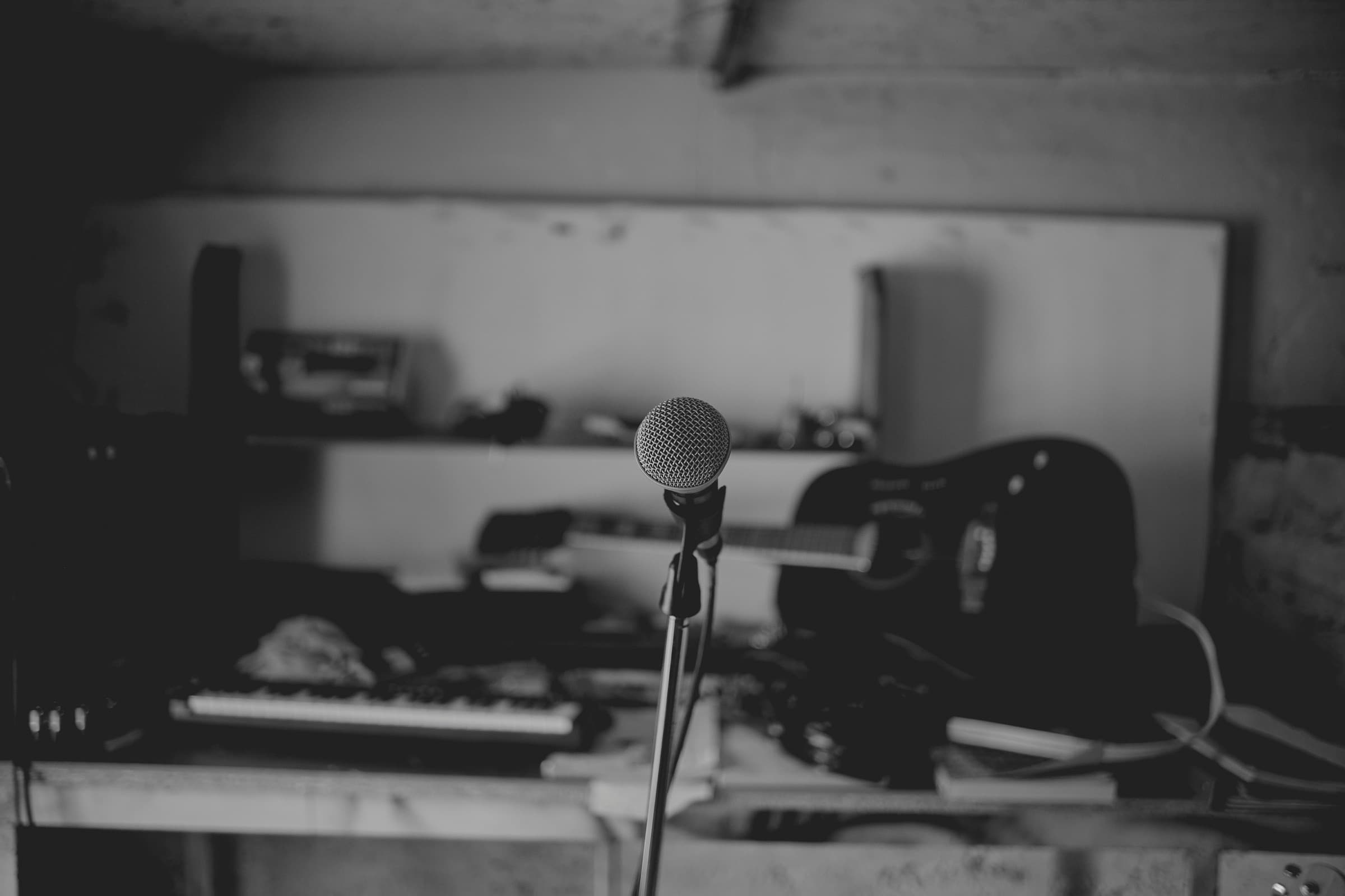 A microphone in front of a guitar and keyboard in a rehearsal room